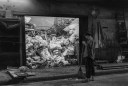 A man sweeping-up at night in front of a recycling business