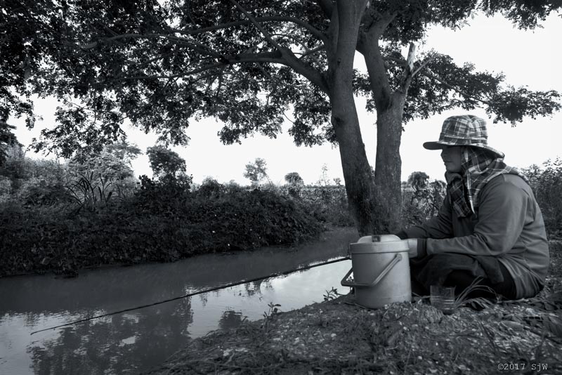 Women sitting while fishing at a waterhole in Ang Tong