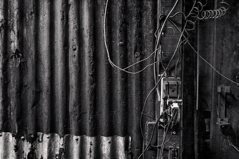 Electrical switch and wiring on a wall of rusted corrugated iron in Bangkok