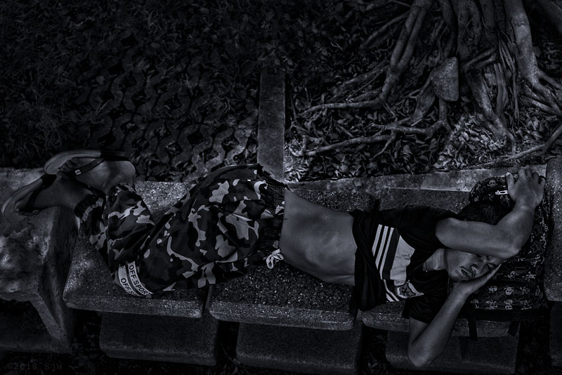 Man sleeping on a park bench in Bangkok